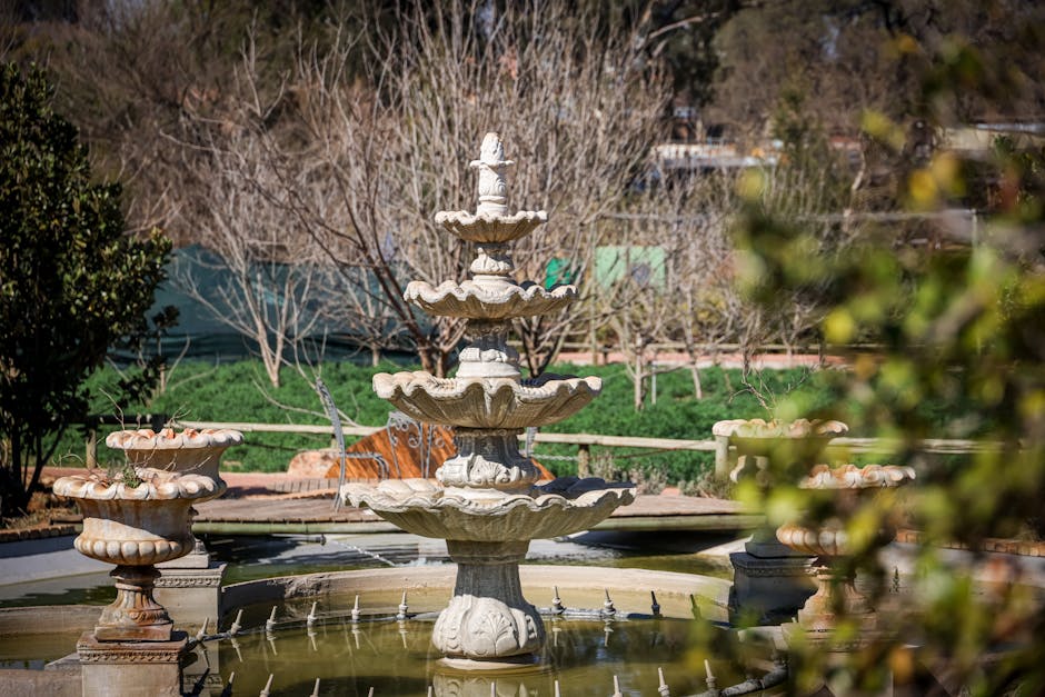 A beautifully crafted tiered fountain enhances the serenity of a lush garden, surrounded by greenery.