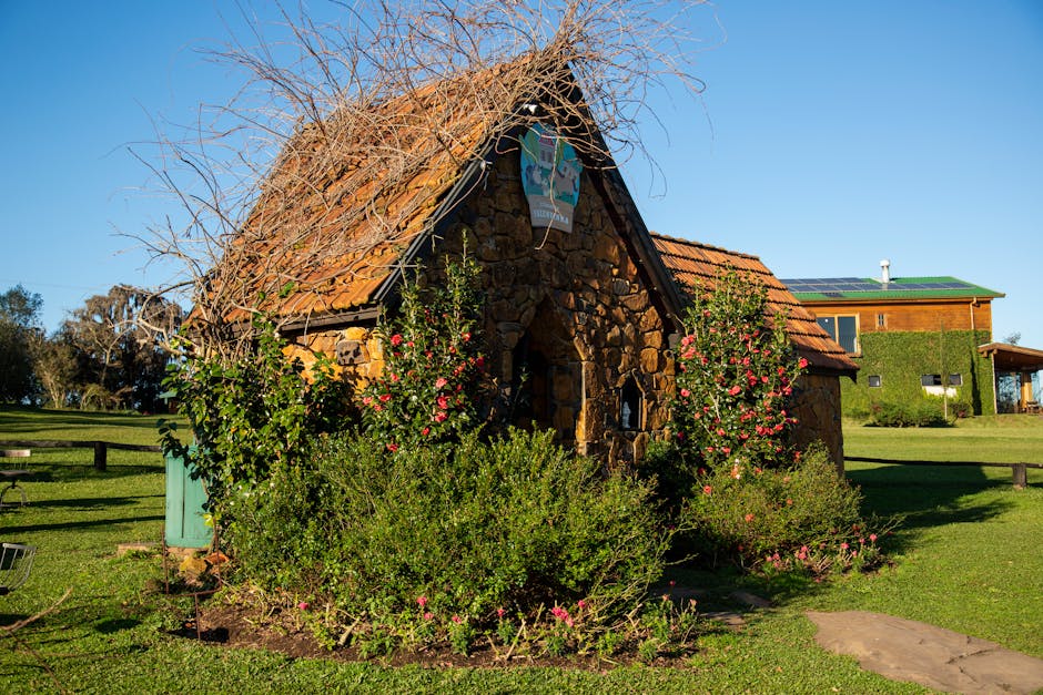 Charming rustic stone cottage surrounded by lush greenery and blue sky.