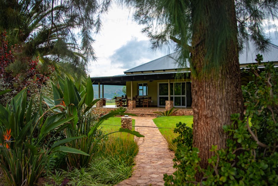 A scenic garden path leads to a charming country house under a cloudy sky.